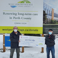 Two men holding an honourary check while wearing protective masks